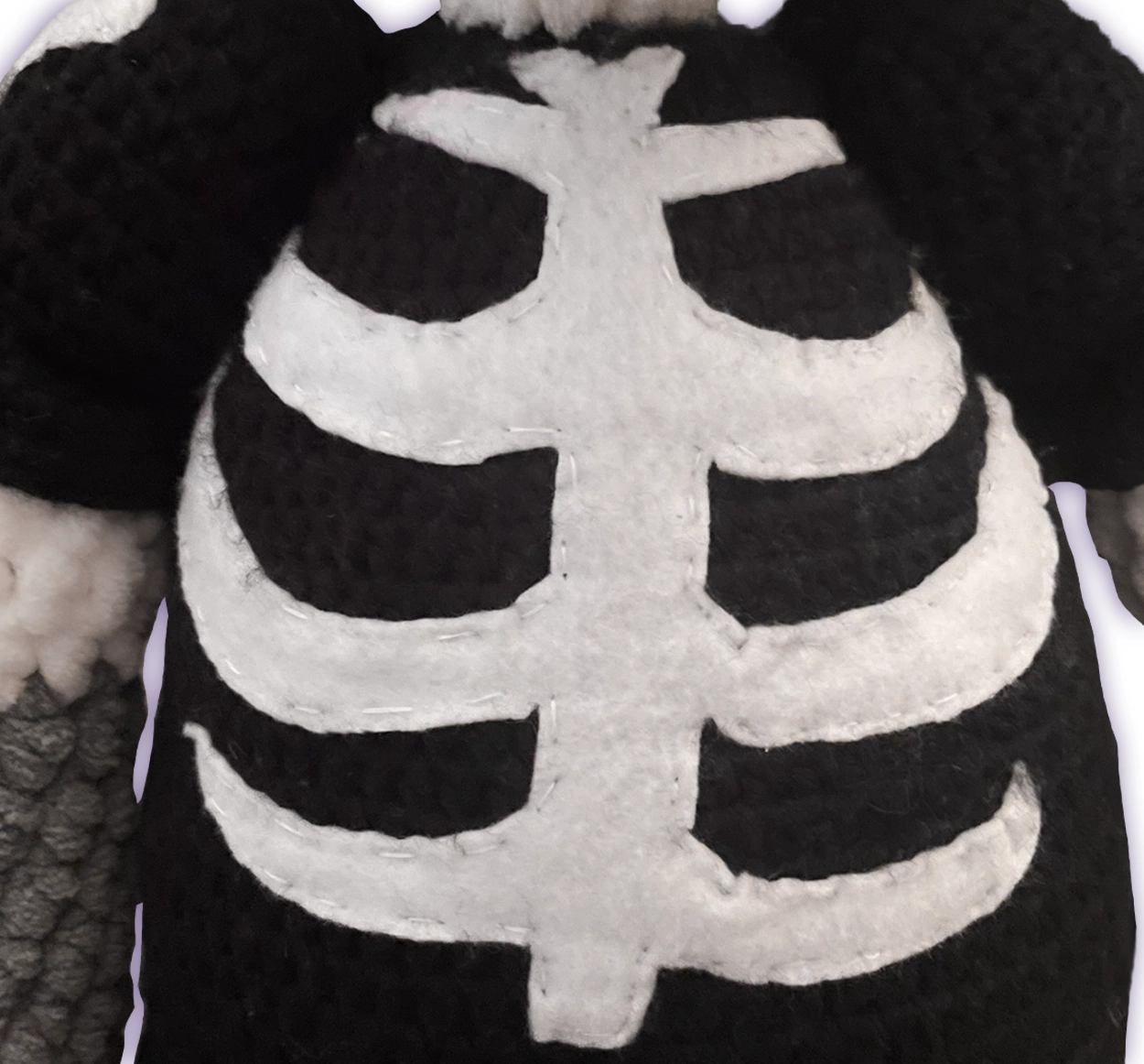 Close-up of crochet fox toon plush skeleton bone shirt, hand-cut white felt details