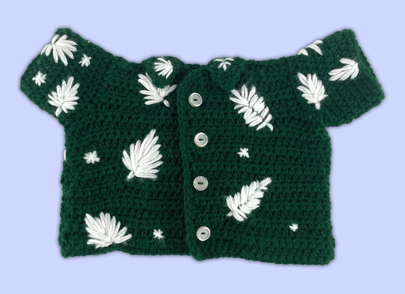 Front view of a green crocheted shirt for a stuffed animal, with small buttons and yarn-stitched leaves.