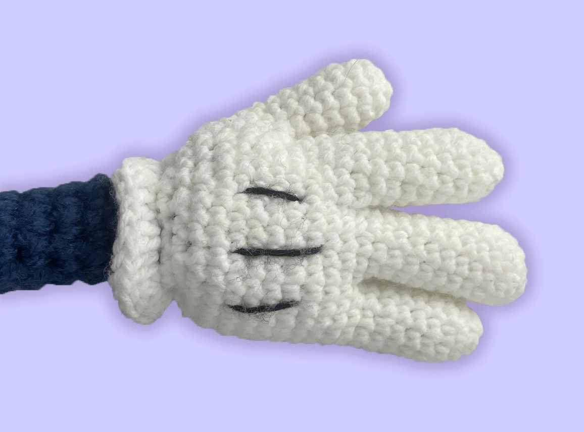 Detailed view of custom crochet plush hand: rounded, glove-style shape inspired by classic cartoon characters. Handmade with tight stitches.