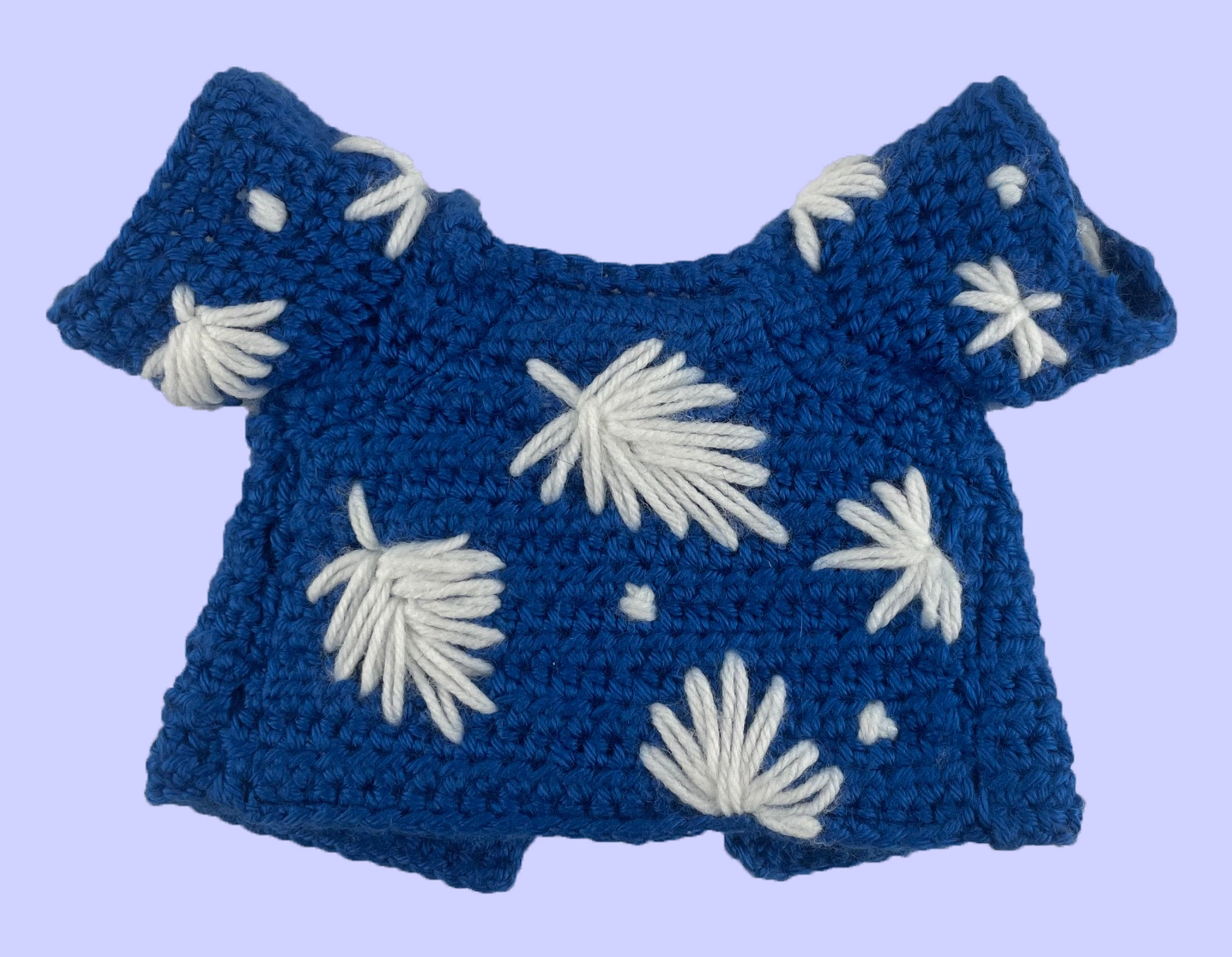 Back of handmade crochet shirt for Toontown plush: embroidered white flowers on royal blue yarn with visible stitches from the lining..