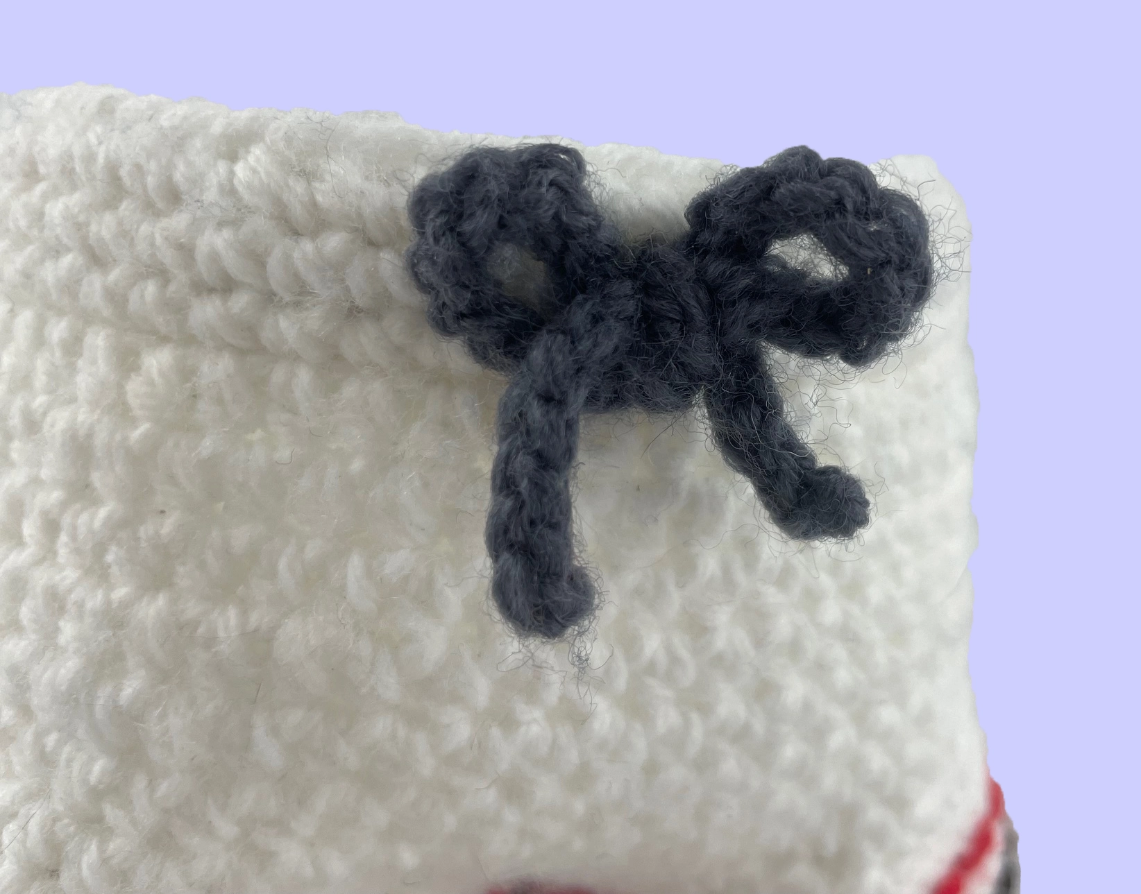 Close-up of decorative drawstring bow on handmade crochet plush shorts, attached to elastic waistband.